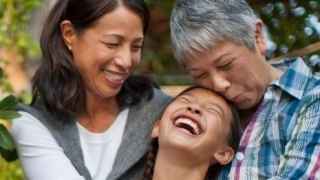 Grandmother, daughter, and granddaughter hugging and sitting on the porch