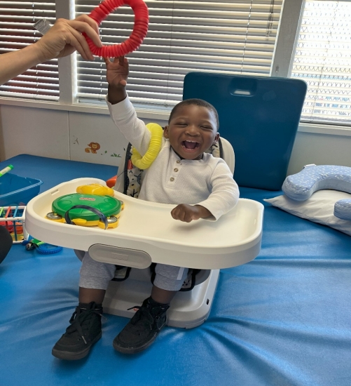 MTP Home Page Photograph of a happy child playing with a toy.